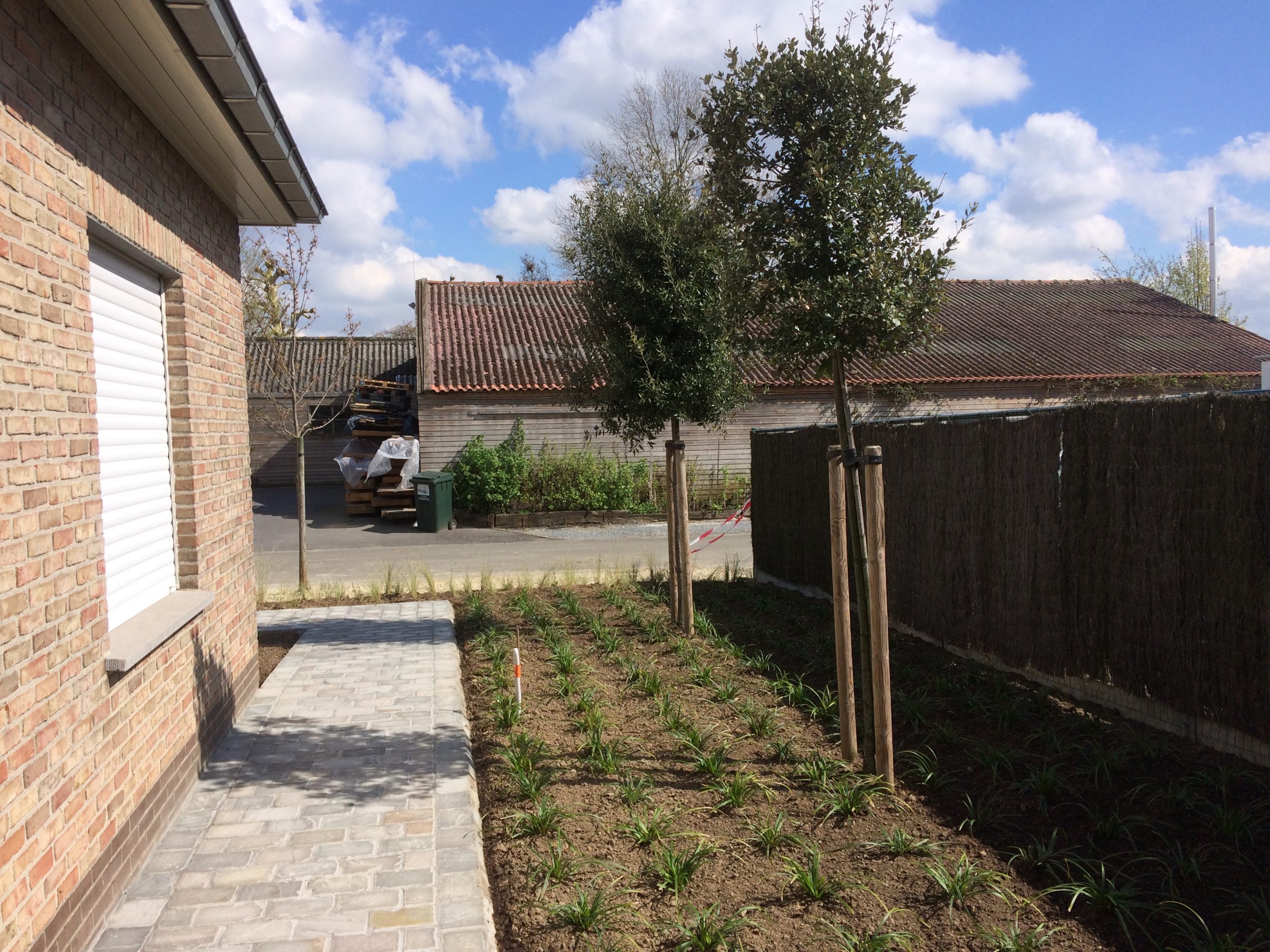 Aangelegde tuin met groen gazon en beplanting door Groenvoorziening Delcroix